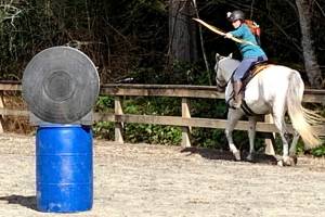 Melissa Davis takes aim with her bow at a target at the Saddle Club.
