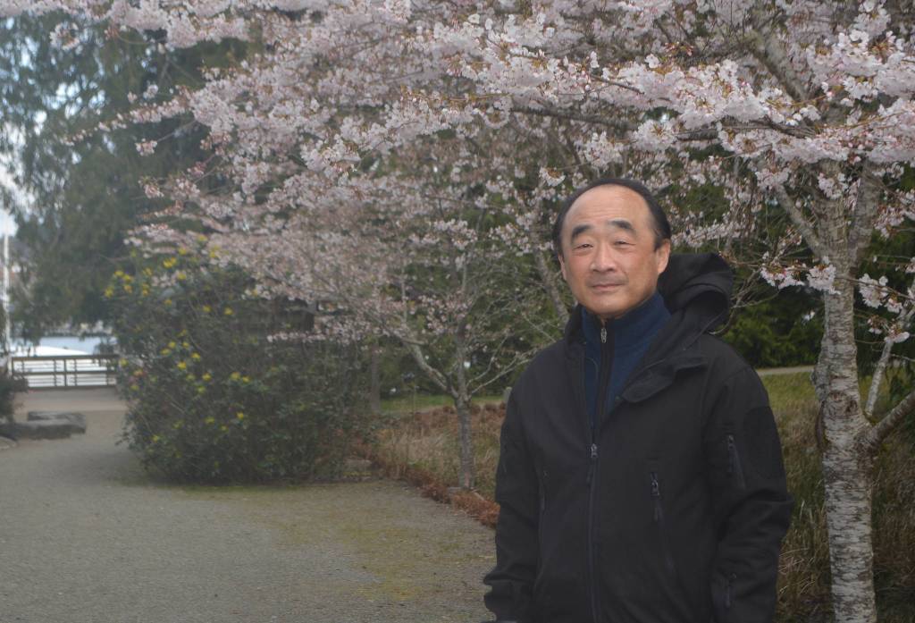 Clarence Moriwaki, with the dock in the background and a cherry tree in blossom in the foreground, talked about the Japanese American concentration camps at the ceremony.