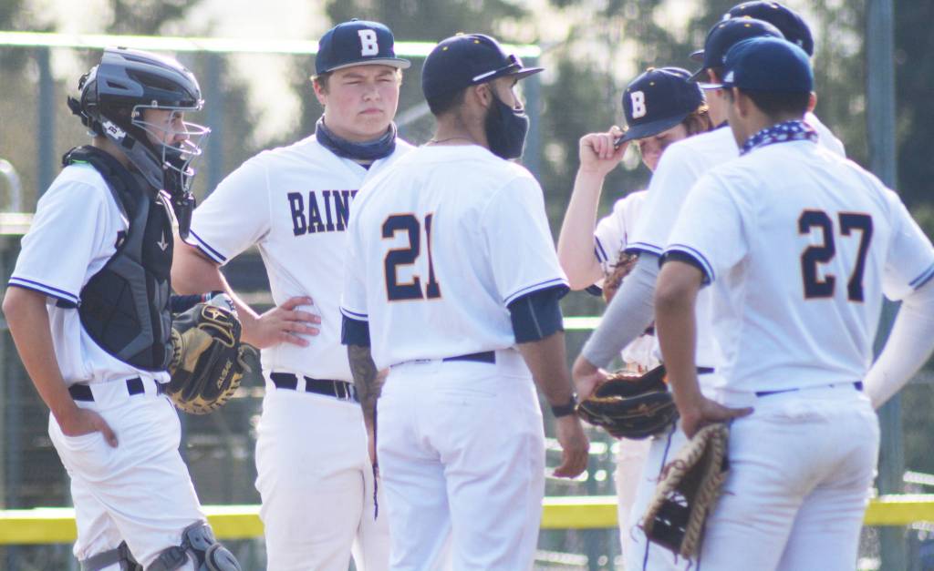 Coach Geoff Brown (2) and the infield meets on the mound to discuss a first and third defensive situation.
