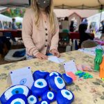 Scottie Carver, 9, prepares her table with hand-painted evil eyes, origami animals and paper lanterns.
