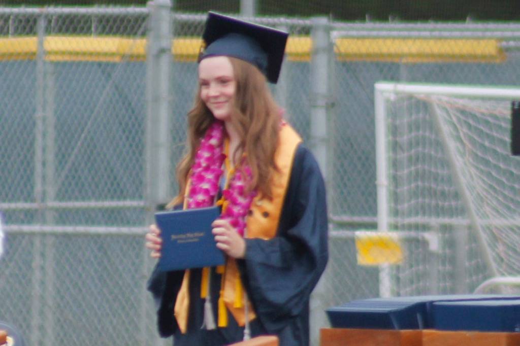 A happy graduate holds up her diploma. Tyler Shuey/Bainbridge Island Review