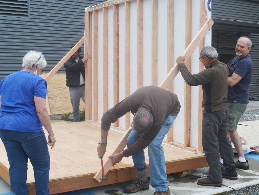 Volunteers hammer in a brace to give the first wall up in place.