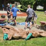 A group of church members digs up gravel into wheelbarrows.