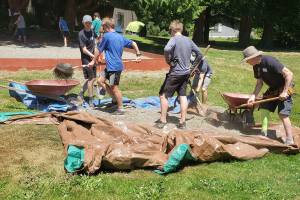A group of church members digs up gravel into wheelbarrows.