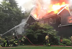 Firefighters work to put out the blaze at the house fire on Bainbridge Island Saturday. Bainbridge Island Fire Department Courtesy Photo