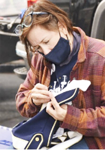 Band mom Kristen Gagnon fastens a loose button on one of the uniforms.