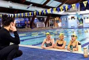 Coach Kristine Cox speaks with swimmers Margaret Hayes, Alexa McDevitt and Emma Solseng.