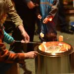Children roast marshmellows for s'mores offered by the Bainbridge Island police officers under the gazebo at Winslow Green during the Annual Tree Lighting event.