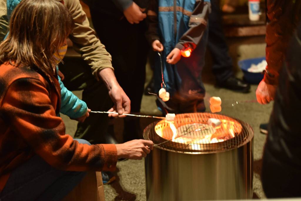 Children roast marshmellows for s'mores offered by the Bainbridge Island police officers under the gazebo at Winslow Green during the Annual Tree Lighting event.