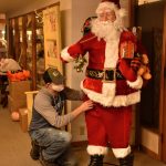 Zev Whitehead, co-owner of Zutto Vintage & Antiques located at 164 Bjune Dr SE in Winslow, readies a motion-controlled Santa to greet visitors at the store entrance.