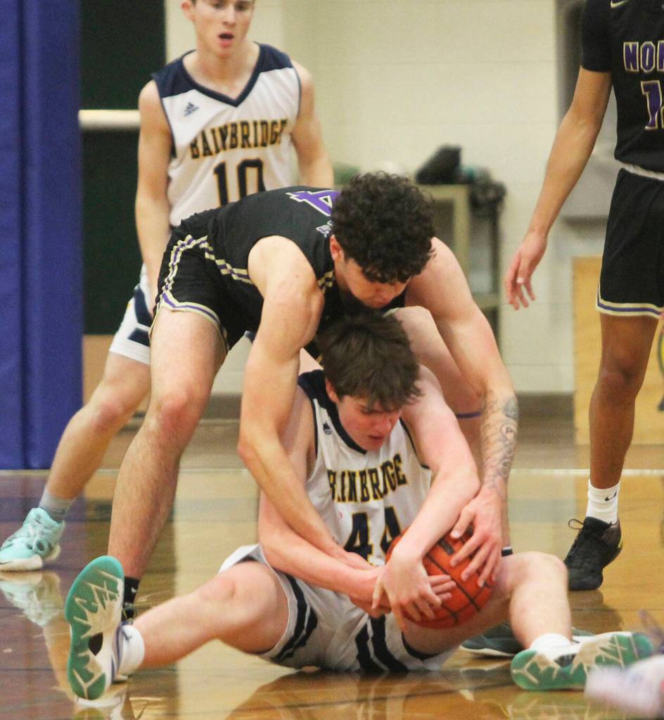 After falling to the floor Noah Davis (44) of Bainbridge gets tied up with Jonas La Tour (4) for a jump ball while Spartan Stanley Intihar (10) watches.