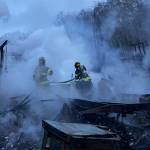 Poulsbo Fire Department firefighters work to extinguish hot spots after fire destroyed a home in the Sawdust Hill neighborhood early Monday morning. One of the occupants has not been accounted for. Courtesy Photo