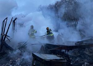 Poulsbo Fire Department firefighters work to extinguish hot spots after fire destroyed a home in the Sawdust Hill neighborhood early Monday morning. One of the occupants has not been accounted for. Courtesy Photo