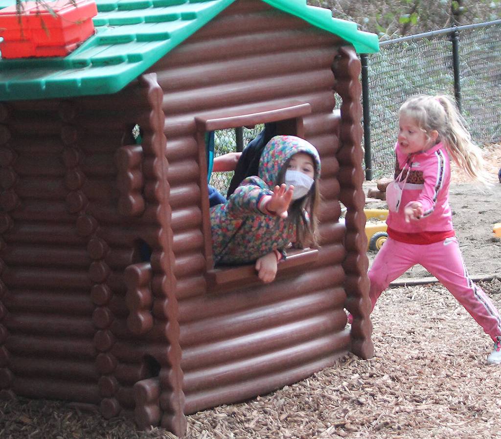 Some girls enjoy a playhouse at the school.