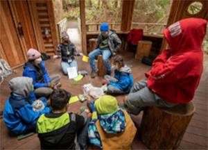 In a fort-like setting, students learn about the environment at IslandWood. Courtesy Photo