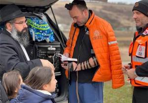 Chabad.org/News courtesy photo
Above: Rabbi Yechiel Shlomo Levitansky and his family, left, talk with paramedics heading to Ukraine. After the rabbi visited with folks via Zoom in Bainbridge his family escaped from the turmoil. At left, Rabbi Mendi Goldshmid, shown here lighting the Menorah, is getting Bainbridge Islanders to help people in Ukraine.