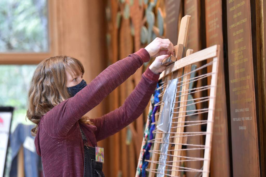 Rachel Knudson from Scrappy Art Lab weaves fabric onto a loom.