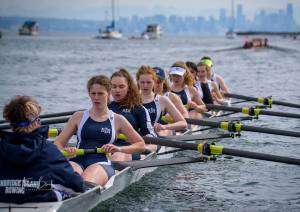 The Bainbridge varsity girls 8+ race with Seattle's skyline in the background.