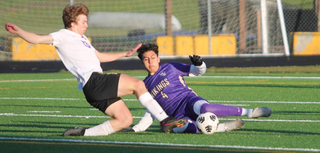 North Kitsap midfielder Diego DeLuna slides to take the ball from Sequim's Brandon Charters in last week's game. Steve Powell/Bainbridge Island Review Photo