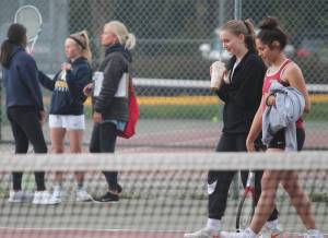 As Kingstons No. 1 doubles team of Kylie Sandstrom and Taliya Caldara cross the court, the Bainbridge team of Aya Gatto and Kristina talk with coach Mary McCombs. Steve Powell/Bainbridge Island Review photos