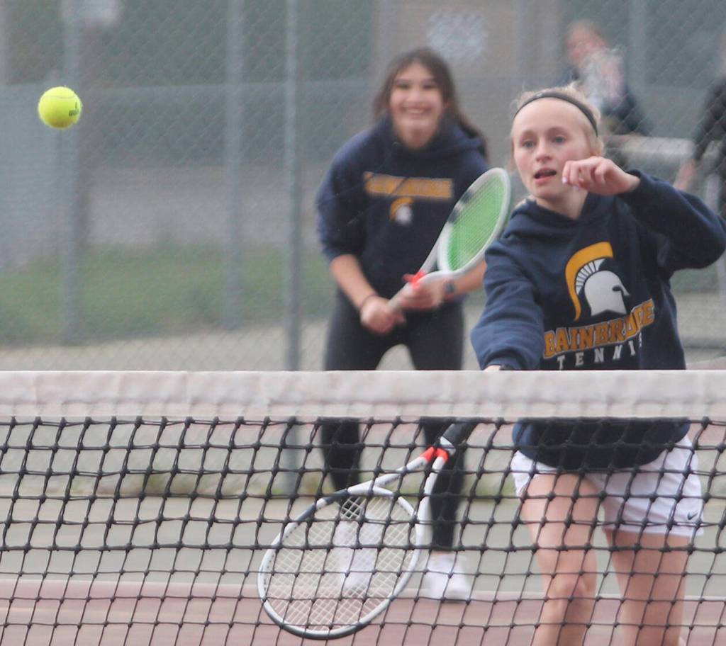 Aya Gatto, in background, smiles as BHS teammate Kristine Walker puts away a backhand volley at the net.