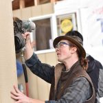 Senior Alexander McAbee nails up siding to one of the tiny houses.