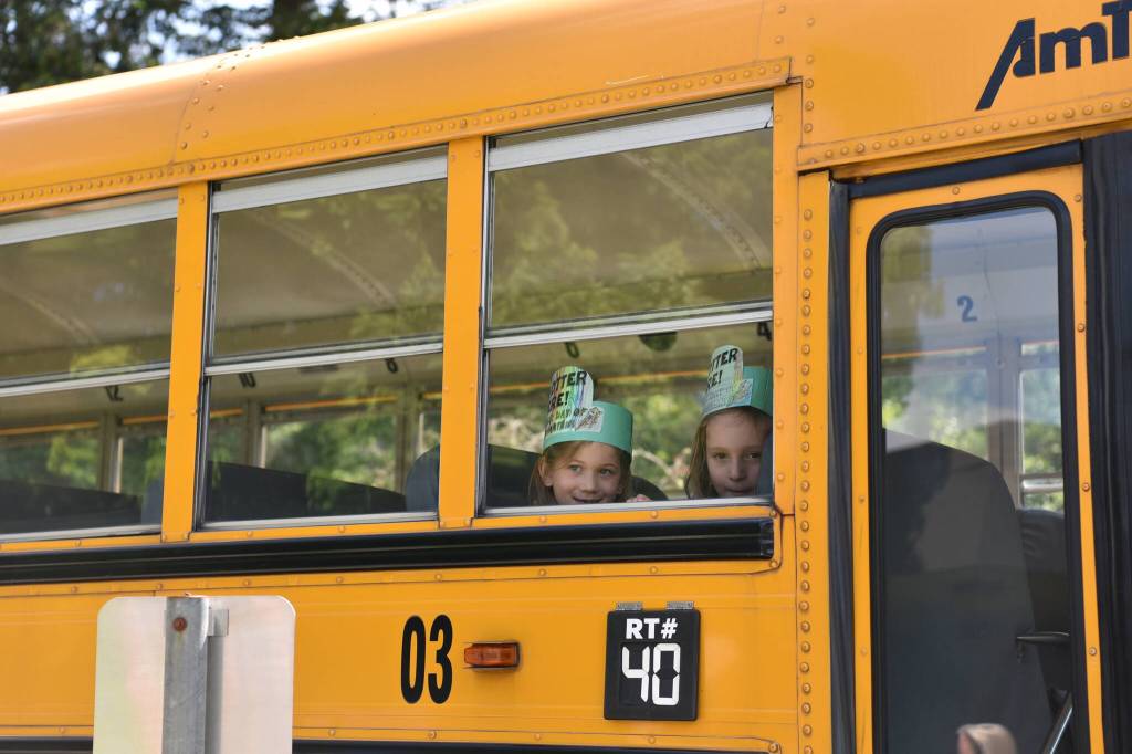 Two kindergarteners ride the bus home on the last day of the school year.