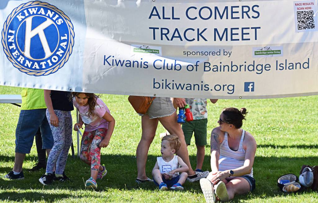 Some folks get some shade under the Kiwanis sign.