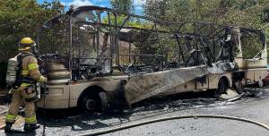 NKF&R firefighter Charlie Hough scans the remains of an RV that burned Tuesday afternoon in Suquamish. Courtesy Photo
