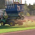 Chip Walker drives a spreader that applies infill to the new turf installed at BHS Memorial Field.