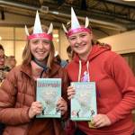 Bea Skipton and Allie Poulson-Houser pose with their Phoebe and her Unicorn books during a book signing event with author Dana Simpson.