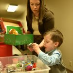 Rachel Garrard helps her son, Luke, 3, fill a box with items for Operation Christmas Child.