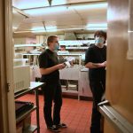 Maggie Rohrbach speaks with a co-worker in the kitchen at the Madison House dining room.