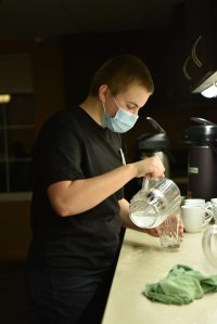 Student server Maggie Rohrbach prepares glasses of water for residents at Madison House on Bainbridge Island. Nancy Treder/Kitsap News Group Photos