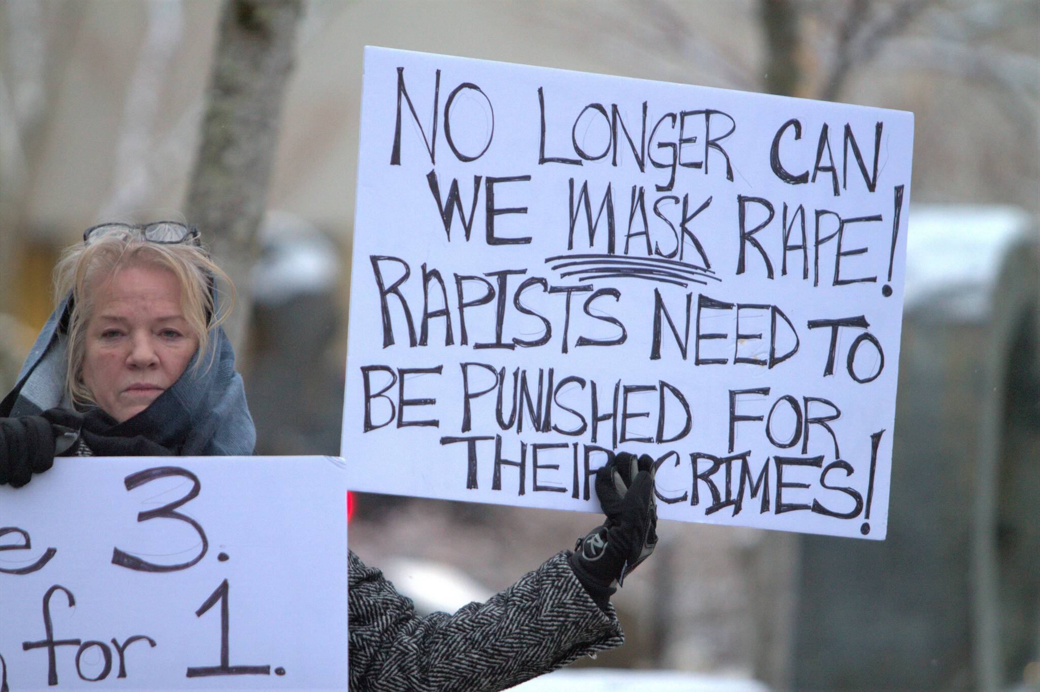 A protester outside the Kitsap County Superior Court holds a pair of signs calling for justice in favor of victims of sexual assault and rape.