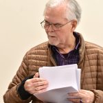 BI poet David Hecker thumbs through a stack of poems during his turn at the podium.