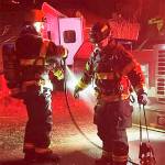 After making short work of a chimney fire NKF&R Lt. Scott Trueblood uses a hose to clean the gear worn by firefighter Tucker Burns. NKF&R Courtesy Photos