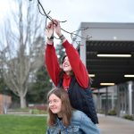 Bainbridge High School seniors Lauren Feeney and Lily Freeman help each other decorate trees with ceramic hearts Feb. 13. BHS senior and ceramic club president Thomas Robinson said they want to 'Share the Love' with students and faculty. The club created 565 ceramic valentines to hang on the trees. Also, students chose specific high school staff to honor and wrote them cards of kindness. Nancy Treder/Kitsap News Group Photos