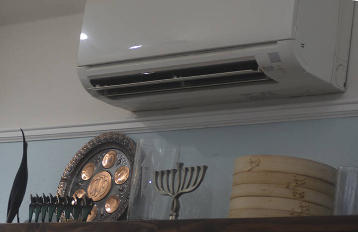 A shelf with decorations on it hangs next to the environmentally friendly heat pump.