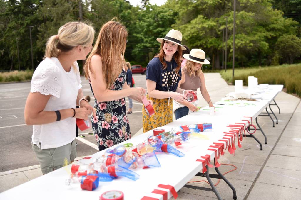 Parent volunteers prepare bubble blowers from recycled bottles and netting.