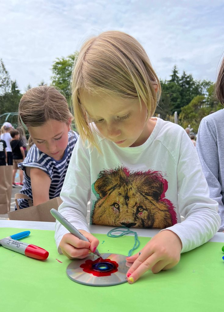 First-grader Daphne Erdman makes a fidget spinner out of a recycled compact disk.