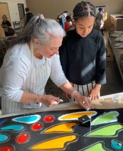 Diane Bonciolini of Mesolini Glass Studio helps fourth-grader Haven Stanley place her fused glass piece into the wings of the Ordway butterfly. Ariana Mohit courtesy photo