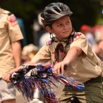 Boy Scouts ride decorated bikes with their troop.