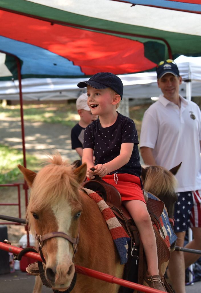 Benjamin Watkins, 3, enjoys a ride a pony in the Kids Zone as his father, George, looks on.