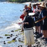 Suquamish tribal members greet canoes with song and drums July 28 on the beach in front of tribe's House of Awakened Culture.