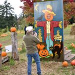 A man takes a picture of a smiling scarecrow.