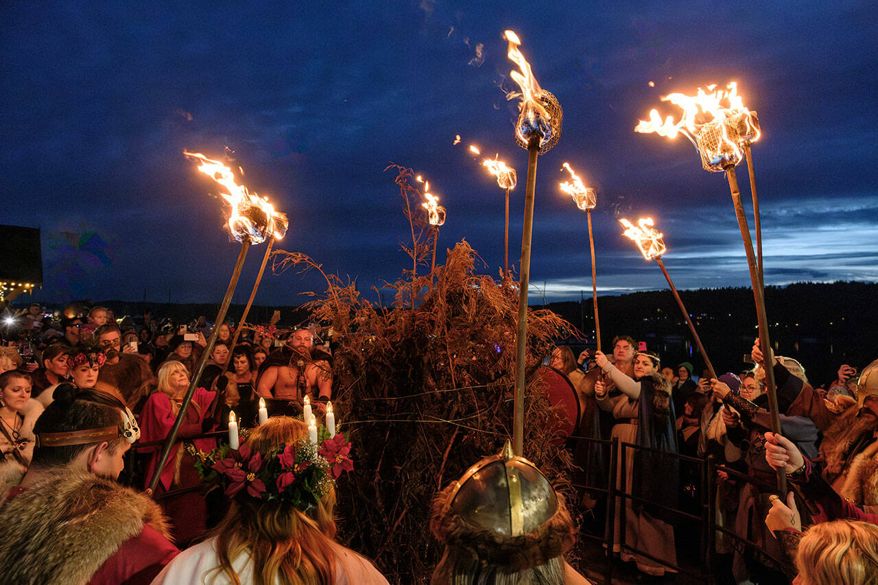 Vikings prepare to light the bonfire with their torches.