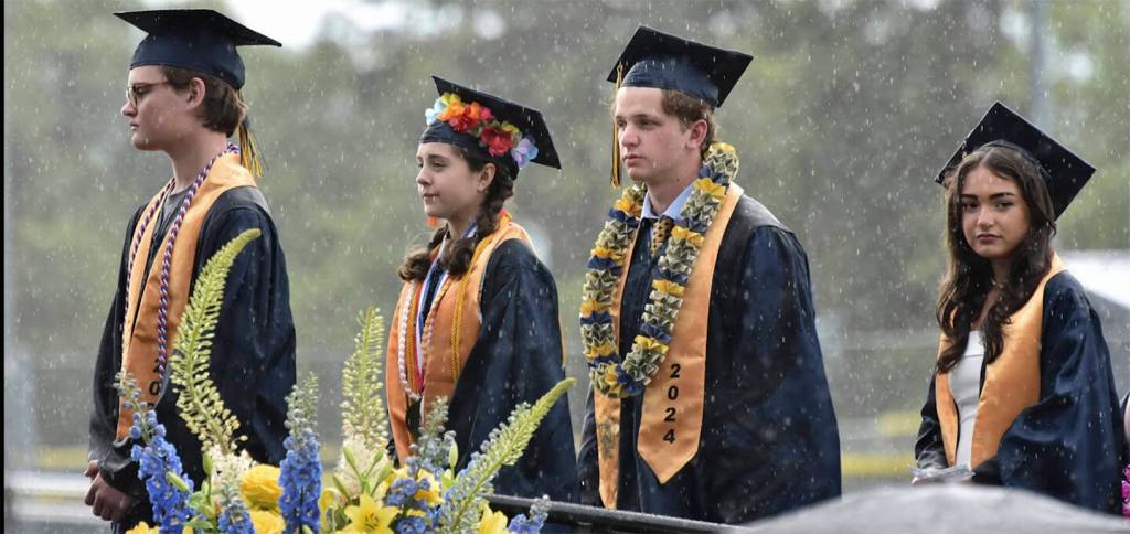 These graduates look none too happy that the rain decided to pour down as they waited to receive their diplomas.