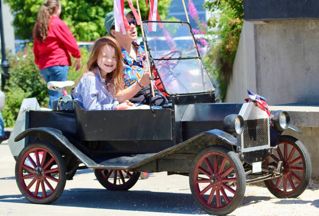 A mini Model T helps lead the way in this year's parade. Otto, in front, had plenty of fun in the passenger seat.