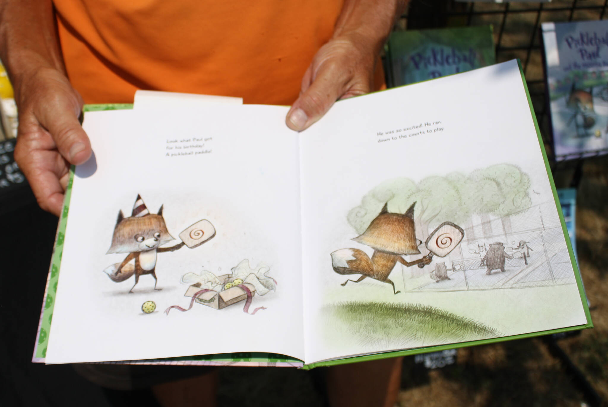 Bill Knopp displays a page from the hit childrens book series, Pickleball Paul, in which a young fox learns valuable life lessons while playing pickleball.